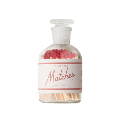 clear glass apothecary-style bottle with white and red matches label; red tip matches inside