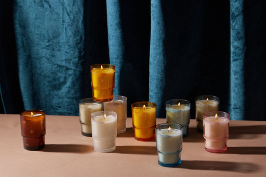10 Candles in the image.  6 different varieties of the Noel Candle are available for purchase.  Candles are on a table with a dark blue curtain behind them