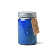 A blue mason jar Paddywax Relish candle labeled “Gardenia & Tuberose” with a metal lid and brown tag sits against a white background, perfect for adding an inviting floral home fragrance to any space.