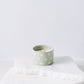 Green ceramic candle with sparkles and white soy wax center with three wicks burning 
