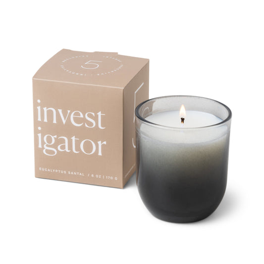 Candle with a vessel of clear glass that fades to black at the bottom; pictured next to the gray box which reads “investigator”