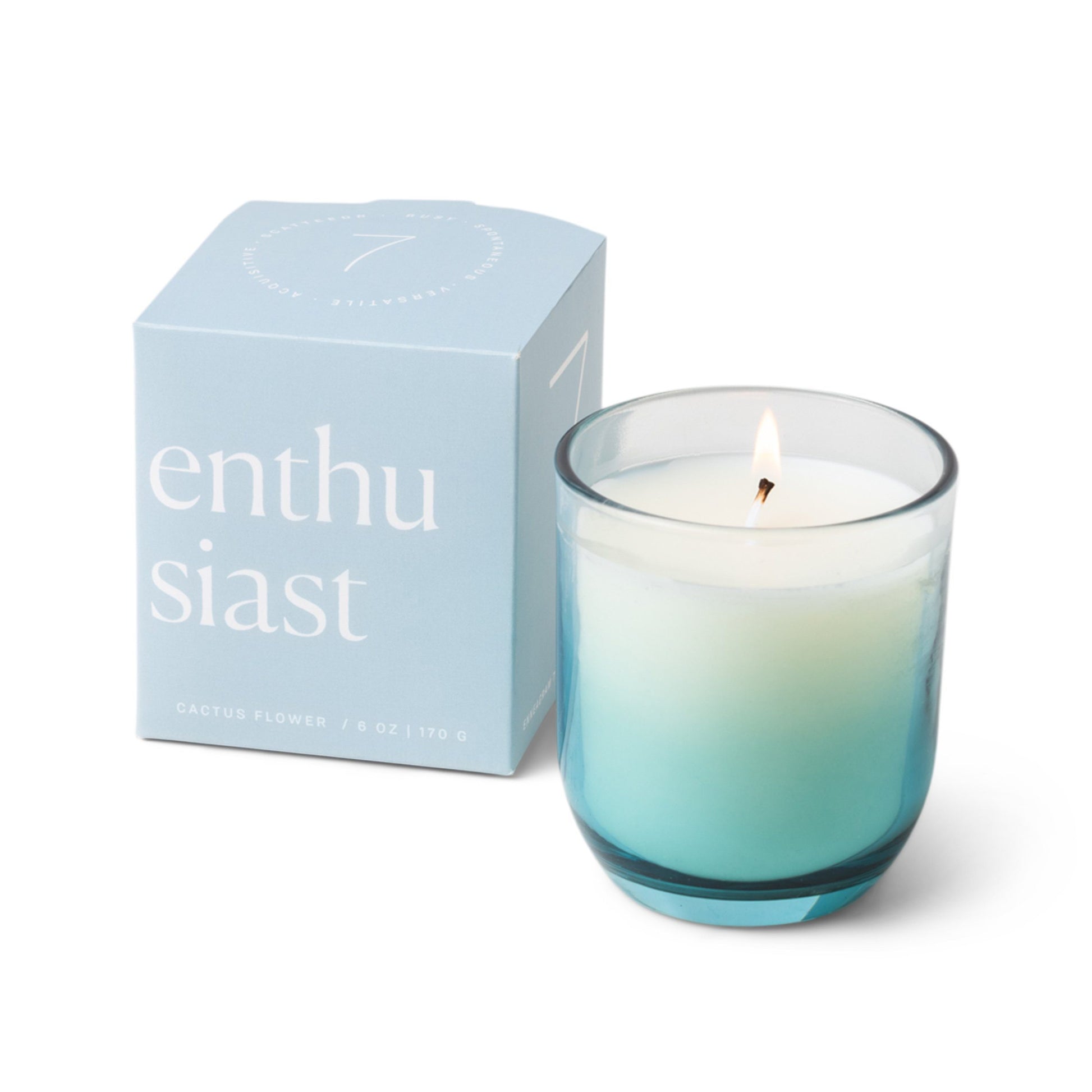 Candle with a vessel of clear glass that fades to turquoise at the bottom; pictured next to the baby blue box which reads “enthusiast”