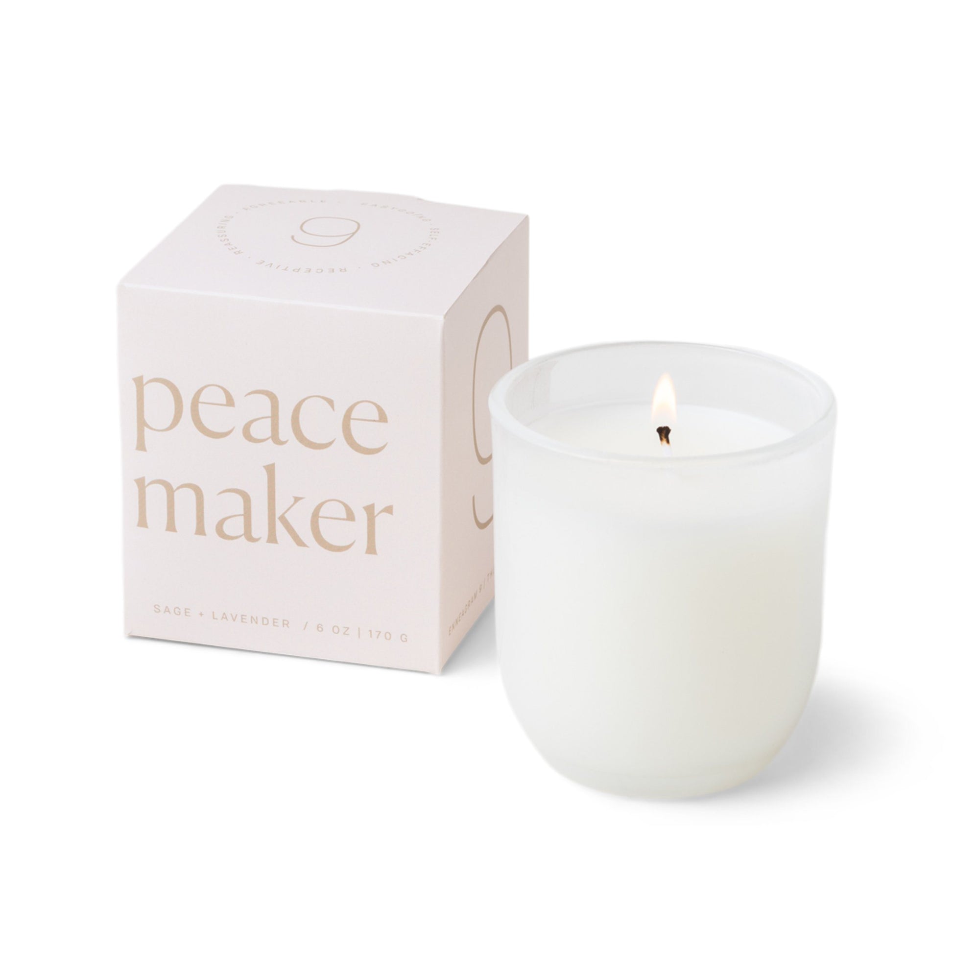 Candle with a vessel of clear glass that fades to white at the bottom; pictured next to the white box which reads “peace maker”