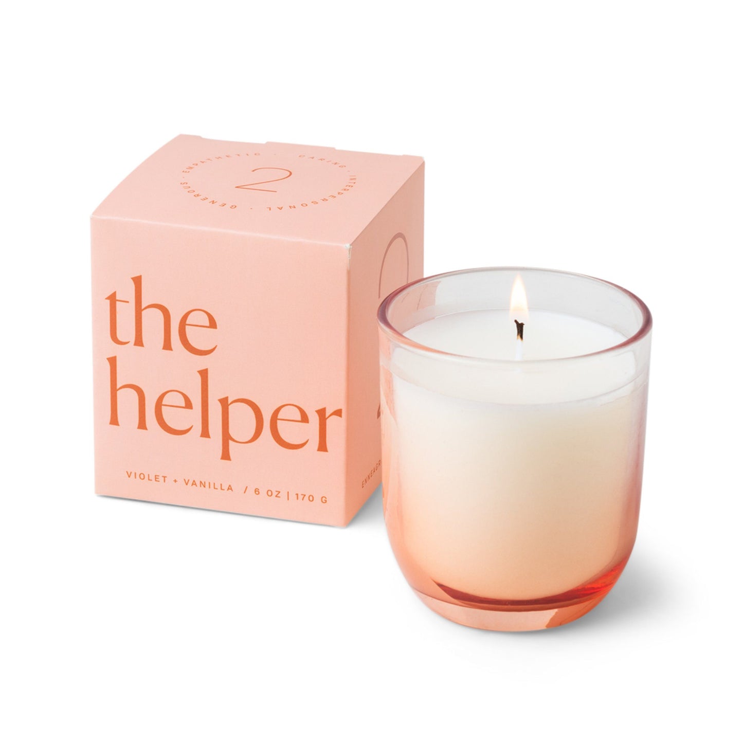 Candle with a vessel of clear glass that fades to an orange-pink at the bottom; pictured next to the pink “the helper” box